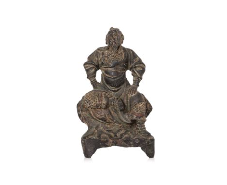 A SEATED BRONZE FIGURE OF GUANDI
Modelled wearing armour and seated on throne, hands at hips and one foot raised, the other r