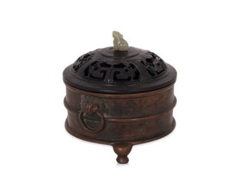 A BRONZE TRIPOD CENSER AND COVER
Circular censer with banded sides and archaistic figural ring lugs, reticulated hardwood cov