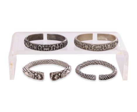 A GROUP OF FOUR CHINESE SILVER BANGLES
Two flat-formed examples decorated in Buddhist emblems, a rope-form example with drago