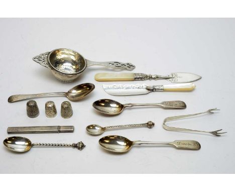 A selection of silver items, including: a tea strainer, two butter knives with mother-of-pearl handles; teaspoons; thimbles a