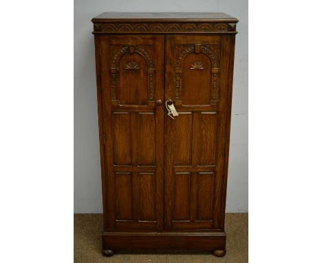 A 20th Century oak cupboard, the rectangular top with lunette carved frieze, above a pair of arcaded panel doors enclosing a 