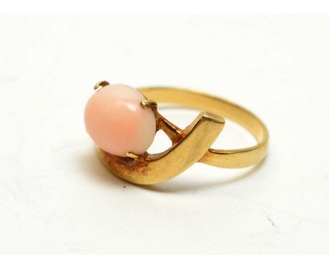 A coral ring, the light pink cabochon on yellow metal shank stamped '14K', ring size O.