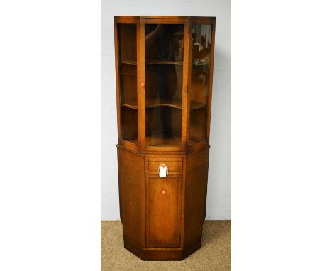 A 20th Century oak corner cabinet, the caddy top above a central glazed cupboard door enclosing two shelves, above a base sec