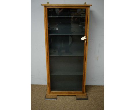 A 20th Century oak display cabinet, the projecting top above a single panel door enclosing five shelves, raised on block feet