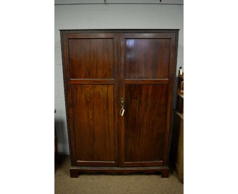 An early 20th Century mahogany wardrobe, the caddy top above a blind fret carved frieze, two panelled doors with hanging spac