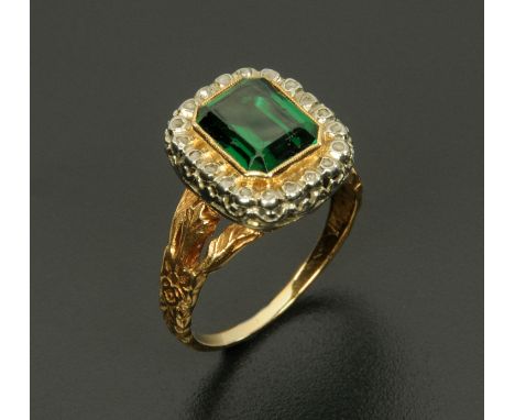 An 18 ct gold ring set with a rectangular cushion cut green stone framed by diamonds, the shank with decorative and pierced s