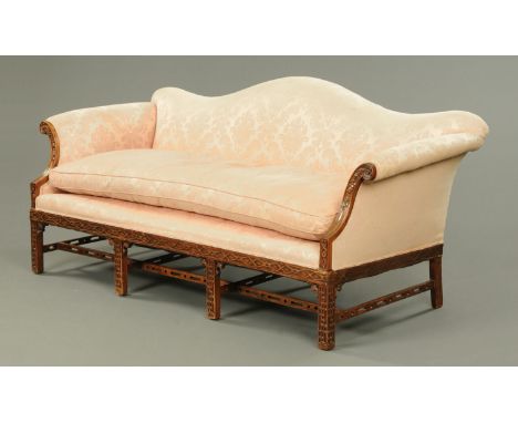 An Edwardian mahogany Chippendale style settee, with arched back, rollover arms and squab cushion upholstered in pink foliate