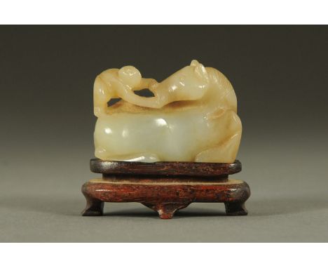 A carved jade figure of a monkey atop a horse, late 19th/20th century, the horse seated and backwards facing whilst the monke
