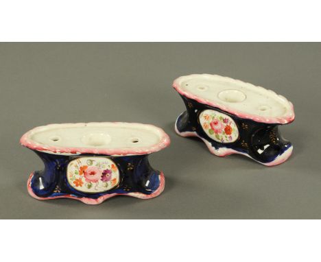A pair of Staffordshire porcelain inkwells, 19th century, each with central well flanked by two pen apertures, framed by a mo