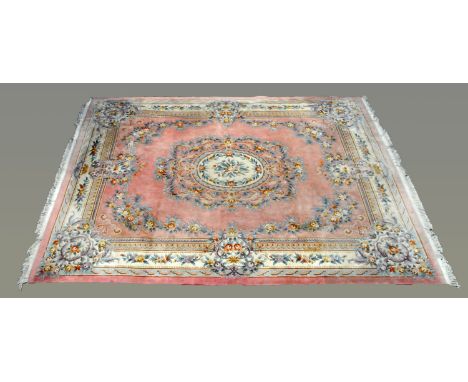 A large Chinese woollen carpet, with pink ground, foliate spandrels and fringed ends.  490 cm (including fringes) x 370 cm (s