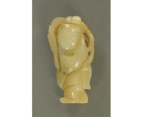 A carved jade figure of a boy, 19th/20th century, holding a leafy branch over his back, the stone a consistent green/grey ton