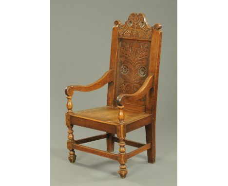 An oak Wainscot chair, with branch and foliate carved cresting rail and back panel, solid seat and raised on turned legs. 