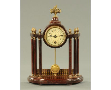 An Edwardian mantle clock, with cast metal floral finial supported on six plain columns with gilt metal acorn finials on a sh