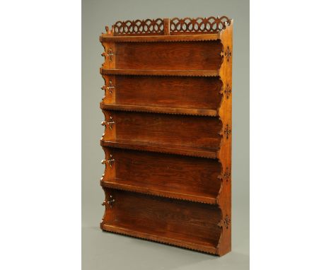 An oak Arts & Crafts open shelf unit, with fretwork pediment above a series of fixed shelves.  Width 117 cm. 