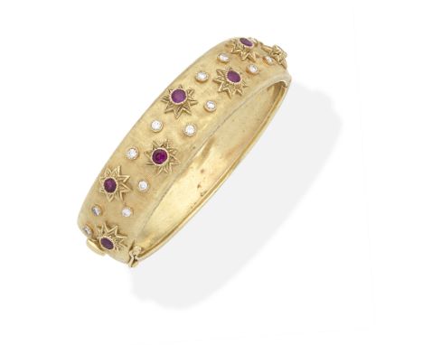 RUBY AND DIAMOND-SET BANGLEThe hinged bangle of fine-line finish, set to the front with circular-cut rubies within raised sta