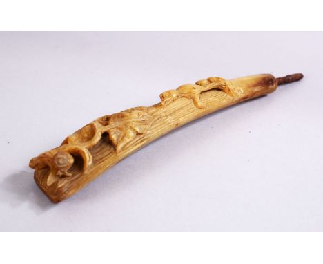 A 19TH CENTURY CARVED RHINOCEROS HORN STICK HANDLE, carved with a four legged animal amongst foliage, 20cm