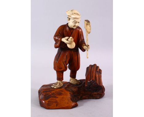 A JAPANESE MEIJI PERIOD CARVED IVORY AND WOOD OKIMONO OF A WOOD CUTTER, stood holding his axe aside a log, with a double gour