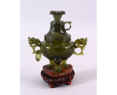 A CHINESE CARVED JADE LIDDED POT &amp; COVER, with twin dragon head handles, on three feet, with a floral finial, on a carved