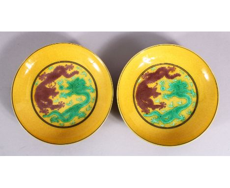 A PAIR OF CHINESE YELLOW GROUND INCISED DRAGON SAUCERS, with green and brown dragons upon yellow ground, the bases with six c