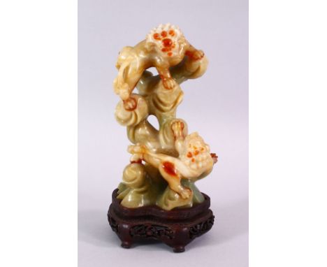 A CHINESE CARVED JADE FIGURE OF TWO LION DOGS, the dogs playing upon wooded outcrops, upon a carved hardwood base, 16cm high 