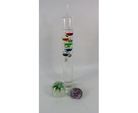 Two art glass paperweights and a Galileo thermometer.