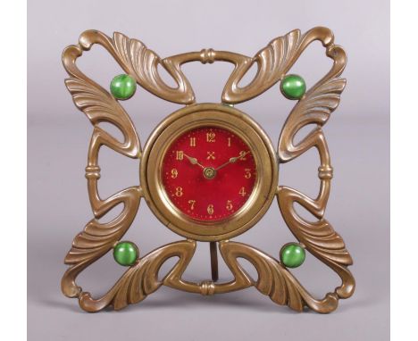 A German Arts &amp; Crafts brass openwork strut clock set with Ruskin type stones with red enamel dial and stamped DRGM.  Mis