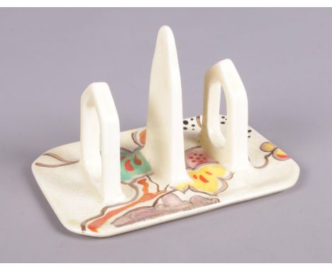 A Clarice Cliff Wilkinson three bar toast rack decorated in the Passion Fruit design. (13cm x 9cm)  Extensive crazing.
