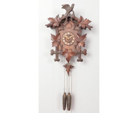 A black forest style cuckoo clock, with carved maple leaf decoration and eagle pediment.  