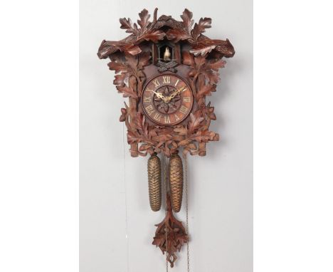 A black forest style cuckoo clock, with extensive carving of an oak tree.  Piece missing from bottom left of carving, pendulu