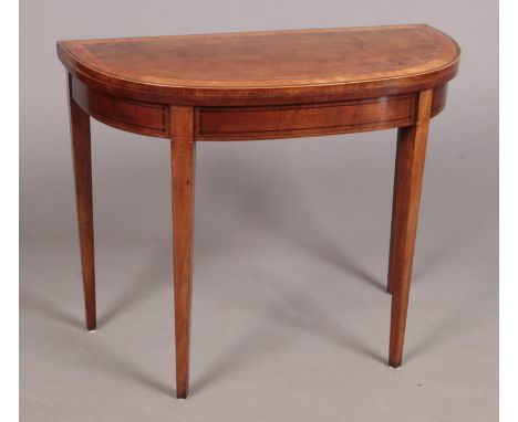 A George III mahogany bow fronted card table raised on square tapering supports. Banded in satinwood and coromandel and with 