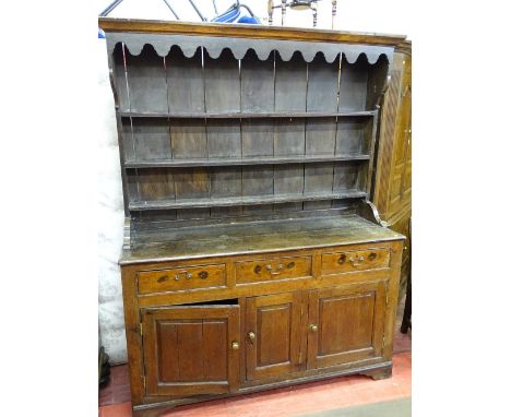 AN ANTIQUE OAK FARMHOUSE DRESSER having a three shelf canopied rack with decorative front frieze, the base section with three