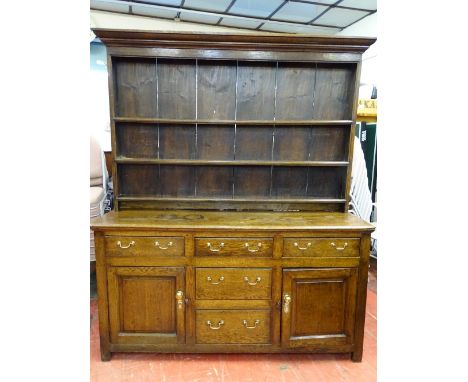 AN EARLY 19th CENTURY OAK DRESSER of joined construction with wide boarded three shelf rack over a base arrangement of three 