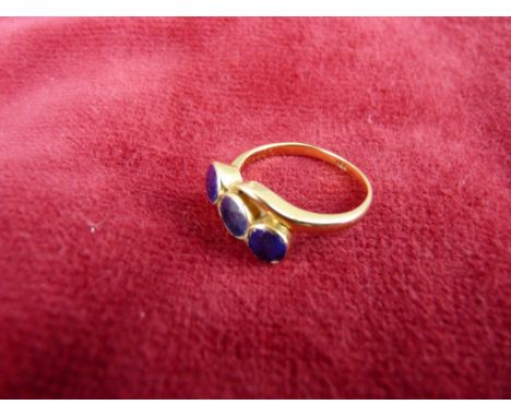 A LADY'S EIGHTEEN CARAT GOLD DRESS RING having three possibly lapis round cut stones in a crossover setting, 3 grms total, si