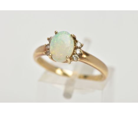 A 9CT GOLD OPAL AND DIAMOND RING, centring on a four claw set oval white opal cabochon, showing flashes of red, green and blu