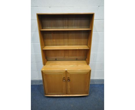 AN ERCOL WINDSOR BLONDE ELM BOOKCASE ON CABINET, with two adjustable shelves, over double cupboard doors, enclosing a cutlery