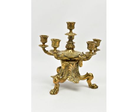 A LATE VICTORIAN BRASS SIX LIGHT CANDLESTICK IN REGENCY STYLE, cast with acanthus, rams heads, anthemion and leaves, on a tri