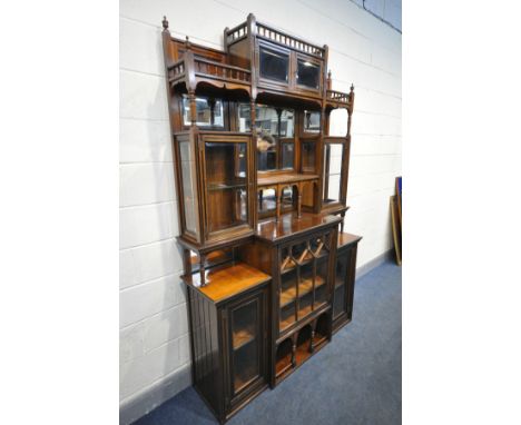 AN EDWARDIAN WALNUT VITRINE, a central bevel edge mirror surrounded by glazed cupboard doors, scrolled aprons, open shelves a