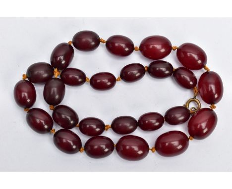 A CHERRY AMBER BAKELITE BEAD NECKLACE, a single row of graduated oval beads, largest measuring approximately 21.6mm x 15.8mm,