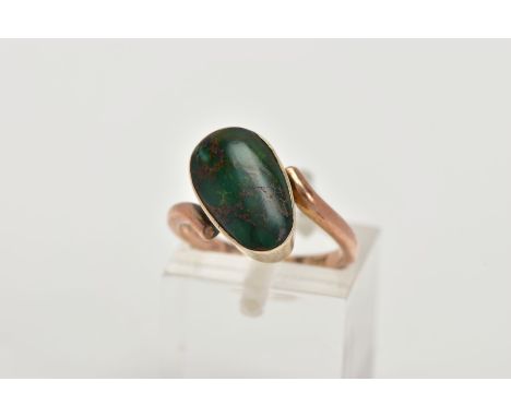 A YELLOW METAL TURQUOISE RING, set with an oval green turquoise cabochon, collet mounted, within crossover shoulders, plain p