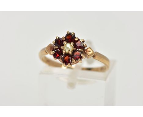 A 9CT GOLD GARNET AND PEARL CLUSTER RING, centring on a seed pearl, within a surround of six circular cut garnets, diamond sh