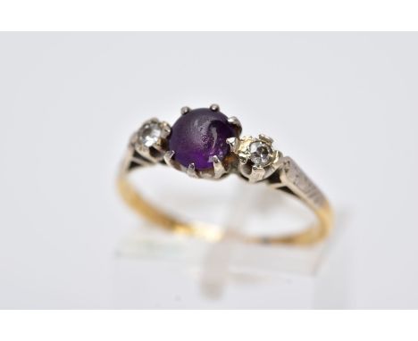 A YELLOW METAL THREE STONE RING, design with a central circular cut purple stone, assessed as paste, flanked with a single cu