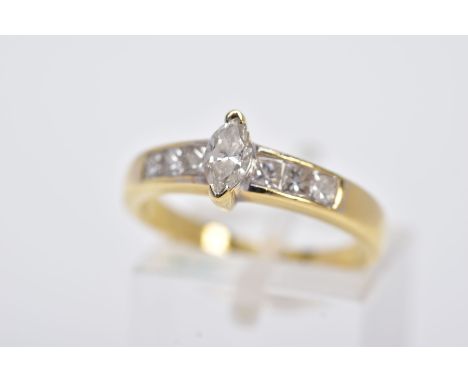 A YELLOW METAL DIAMOND RING, designed with a central raised, marquise cut diamond, flanked with princess cut diamond detailed