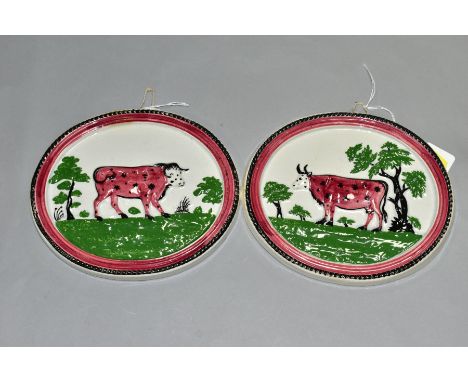 A PAIR OF EARLY 19TH CENTURY STAFFORDSHIRE POTTERY PLAQUES OF OVAL FORM, moulded in relief with a cow facing left and a bull 