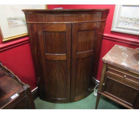 A George III flame mahogany bow fronted wall hanging corner cabinet, twin panelled doors opening to reveal painted interior s