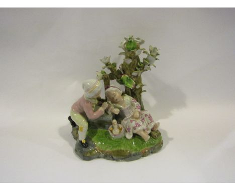 A 19th Century ceramic figural group depicting a boy and girl relaxing by a tree. Crossed swords mark to base A/F. 20cm tall 