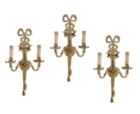 A set of three Continental gilt metal twin light wall appliques in Louis XVI taste, modern, each ribbon tied backplate issuin