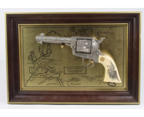 Revolver: A Franklin Mint (?) copy of the Colt .45 S.A. Revolver carried by Gen George S. Pattern JR. Displayed on a frame wi