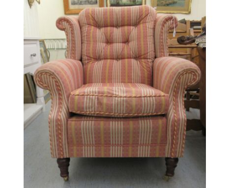 A modern Greensmith upholstered wingback fireside chair with level, scrolled arms and a cushioned seat, in part buttoned cord