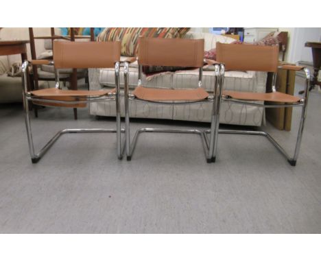 A set of three modern open arm office reception chairs with sprung, tubular stainless steel framed and light brown faux hide 