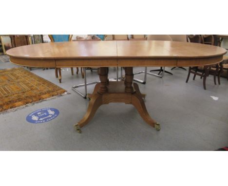A modern light oak dining table of traditional 19thC design, raised on four uniformly spaced columns, on a platform, a splaye